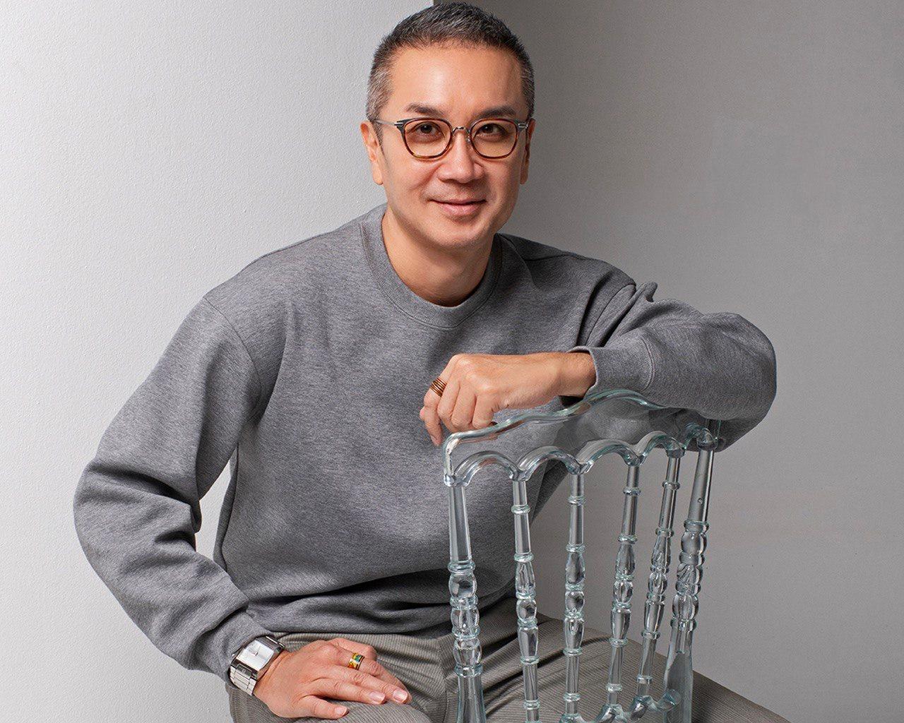 Daniel Tan Boon Hwee seated beside a clear chair in a grey sweatshirt